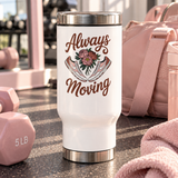 A white stainless steel travel mug with a silver lid and base, printed with "Always Moving" in brown script around a bouquet of pink peonies between a pair of pink and white sneakers.