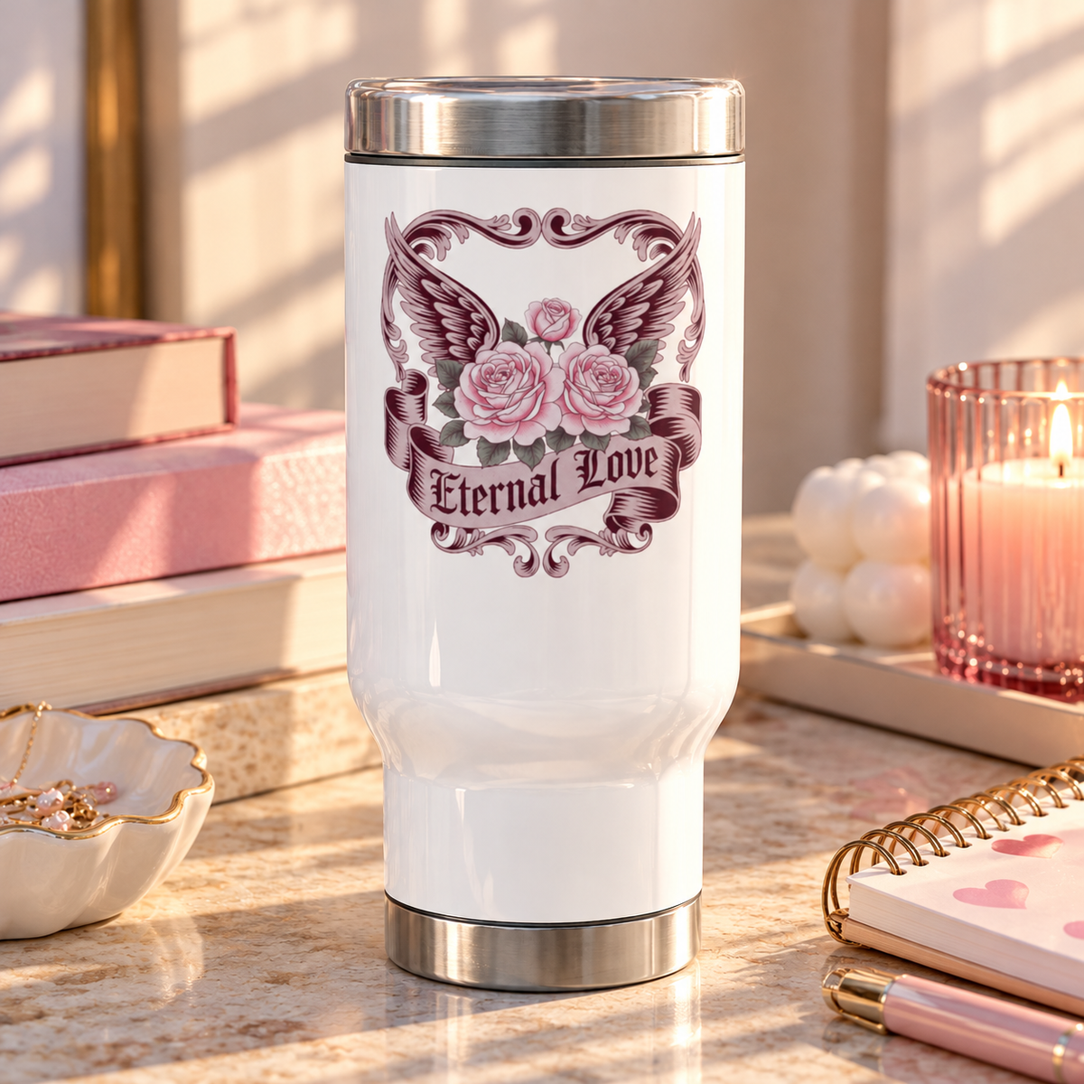 A white stainless steel travel mug with a silver lid and base, printed with pink roses in front of dark burgundy wings, framed by ornate vintage scrollwork, above a banner reading "Eternal Love".