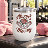 A white stainless steel stemless wine tumbler with a clear push-on lid, printed with "Always Moving" in brown script around a bouquet of pink peonies between a pair of pink and white sneakers.