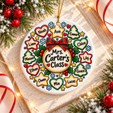 A round white ceramic Christmas ornament on a gold string, printed with a red plaid bow over a circle reading a sample "Mrs. Carter's Class", ringed by heart, star and tree-shaped tags with sample student names, holly, snowflakes and gold stars.
