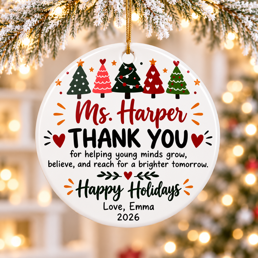 A round white ceramic Christmas ornament on a gold string, printed with a row of five decorated Christmas trees above a sample teacher name in red script, "THANK YOU for helping young minds grow, believe, and reach for a brighter tomorrow", "Happy Holidays" and a "Love" signature with "2026".