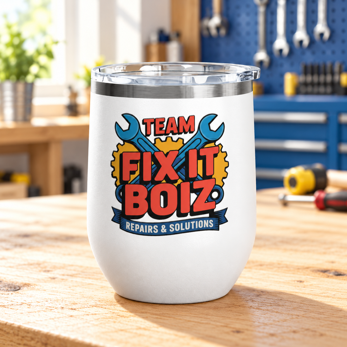 A white stainless steel stemless wine tumbler with a clear push-on lid, printed with "TEAM FIX IT BOIZ" in bold red lettering over crossed blue wrenches and yellow gears, above a "REPAIRS & SOLUTIONS" banner.