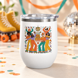A white stainless steel stemless wine tumbler with a clear push-on lid, printed with a group of roller skaters in 70s flares dancing around a tiered birthday cake under a disco ball, in orange, teal, mustard and lavender.