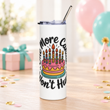 A white stainless steel skinny tumbler with a clear lid and metal straw, printed with "One More Candle Won't Hurt" in black script around a pink and yellow birthday cake with striped lit candles.