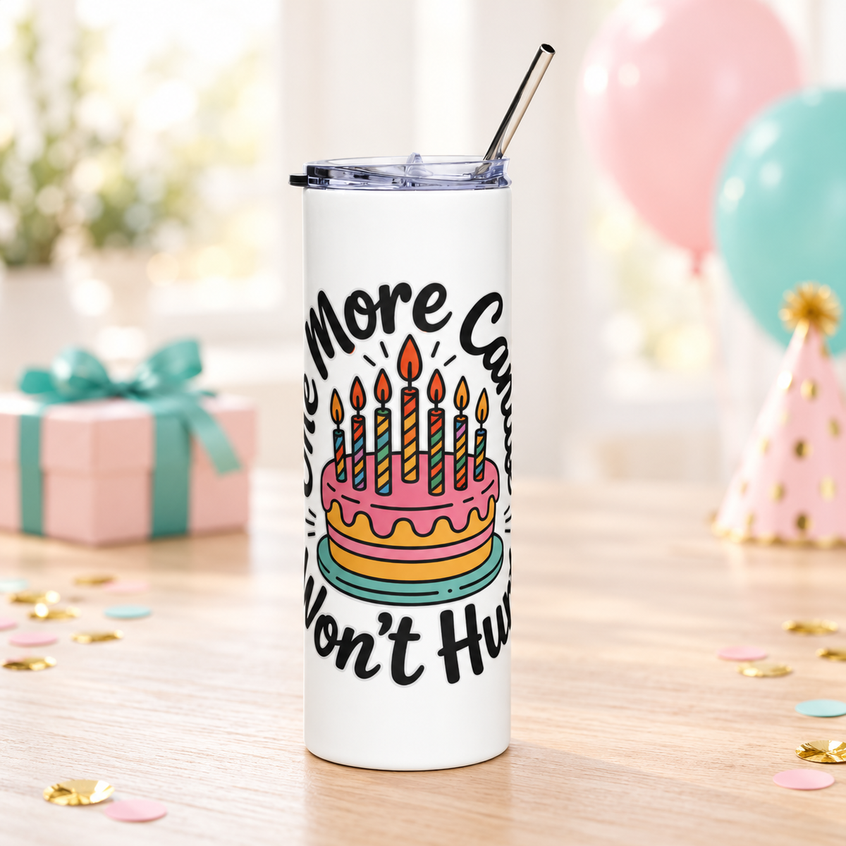 A white stainless steel skinny tumbler with a clear lid and metal straw, printed with "One More Candle Won't Hurt" in black script around a pink and yellow birthday cake with striped lit candles.