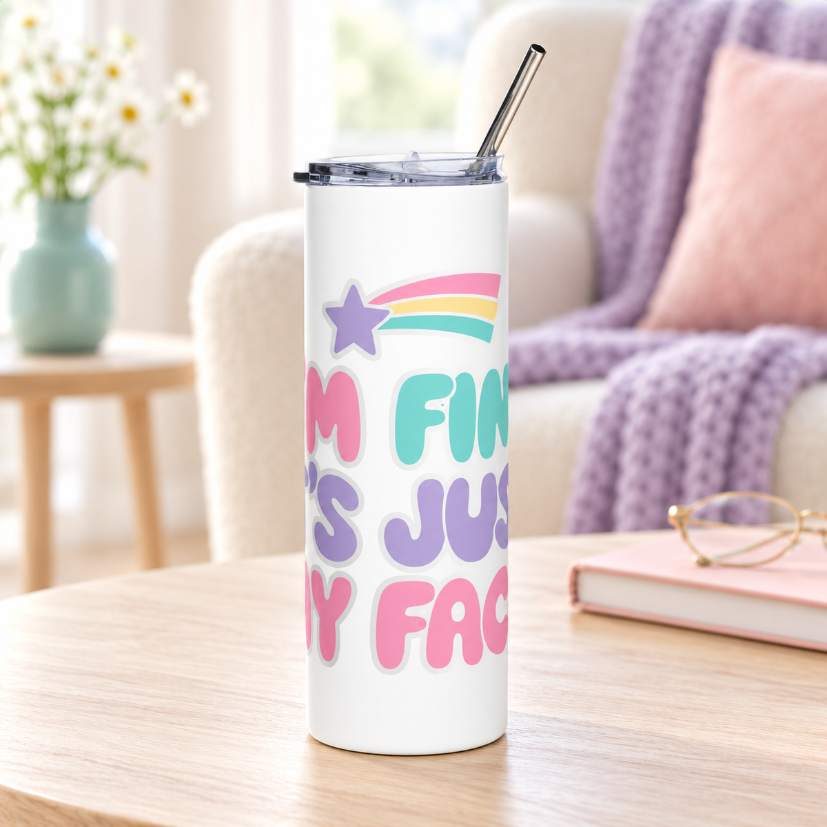 A white stainless steel skinny tumbler with a clear lid and metal straw, printed with "I'M FINE. IT'S JUST MY FACE." in pink, mint and lavender bubble letters under a rainbow shooting star.