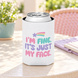 A white can cooler on a drink can, printed with "I'M FINE. IT'S JUST MY FACE." in pink, mint and lavender bubble letters under a rainbow shooting star.