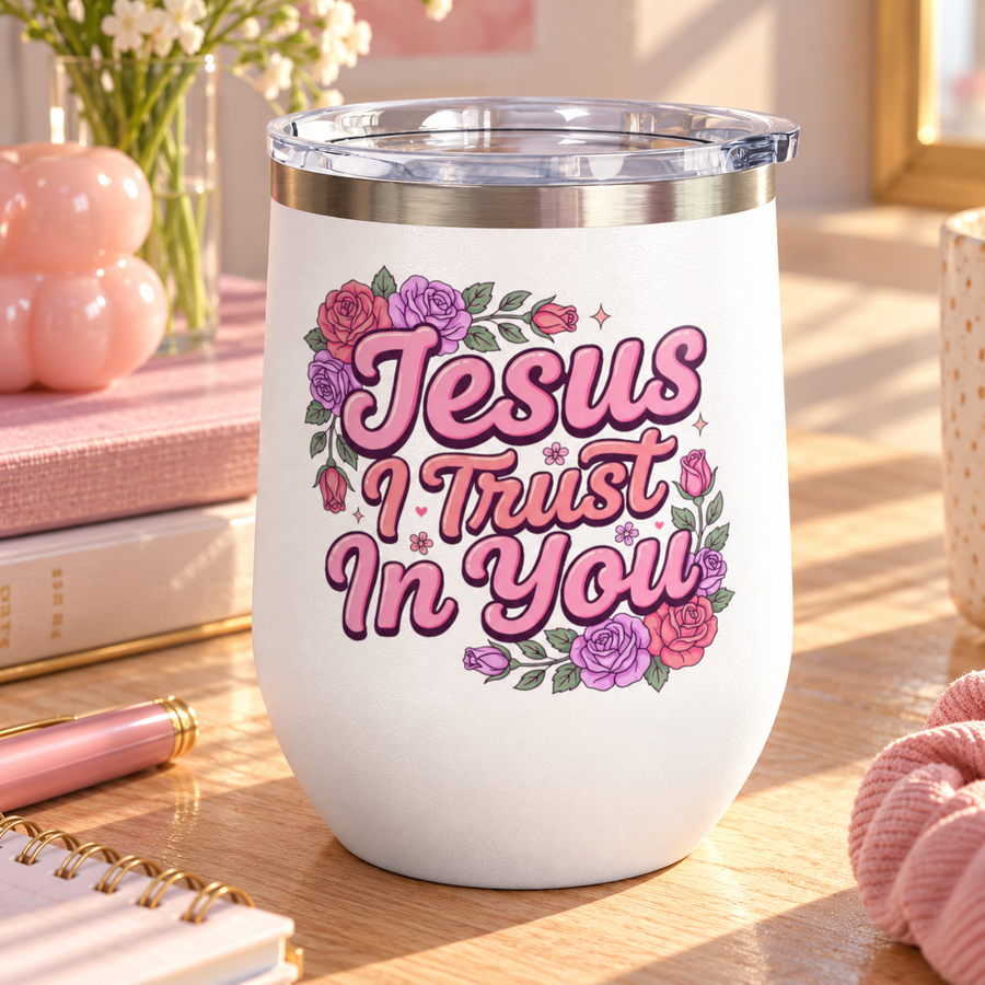 A white stainless steel stemless wine tumbler with a clear push-on lid, printed with "Jesus I Trust In You" in pink retro script framed by pink, red and purple roses and greenery.