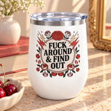 A white stainless steel stemless wine tumbler with a clear push-on lid, printed with a cheeky adult slogan ending "& FIND OUT" in bold black lettering on a cream circle, ringed by red roses, lightning bolts, flames and cherries.