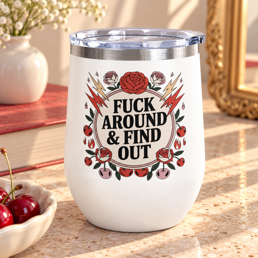 A white stainless steel stemless wine tumbler with a clear push-on lid, printed with a cheeky adult slogan ending "& FIND OUT" in bold black lettering on a cream circle, ringed by red roses, lightning bolts, flames and cherries.