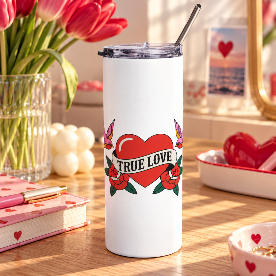 A white stainless steel skinny tumbler with a clear lid and metal straw, printed with a red heart wrapped in a "TRUE LOVE" banner between two red roses, with a pink swallow on each side, in retro tattoo style.
