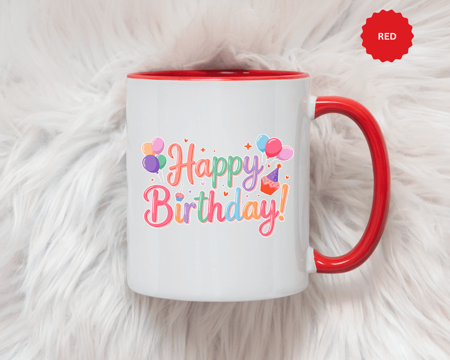 A white ceramic mug with a colored handle and interior, printed with "Happy Birthday!" in pastel rainbow script with bunches of balloons, a cupcake with a party hat, hearts and sparkles.