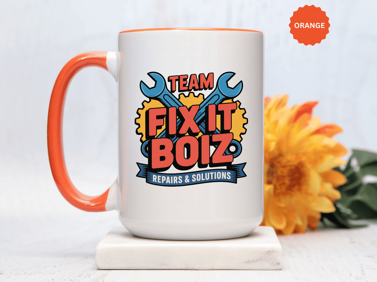 A white ceramic mug with a colored handle and interior, printed with "TEAM FIX IT BOIZ" in red lettering over crossed blue wrenches and yellow gears, above a blue "REPAIRS & SOLUTIONS" banner.