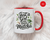 A white ceramic mug with a colored handle and interior, printed with "Just a Girl who loves Matcha" in black script with a green matcha cup, a bamboo whisk and tea leaves.