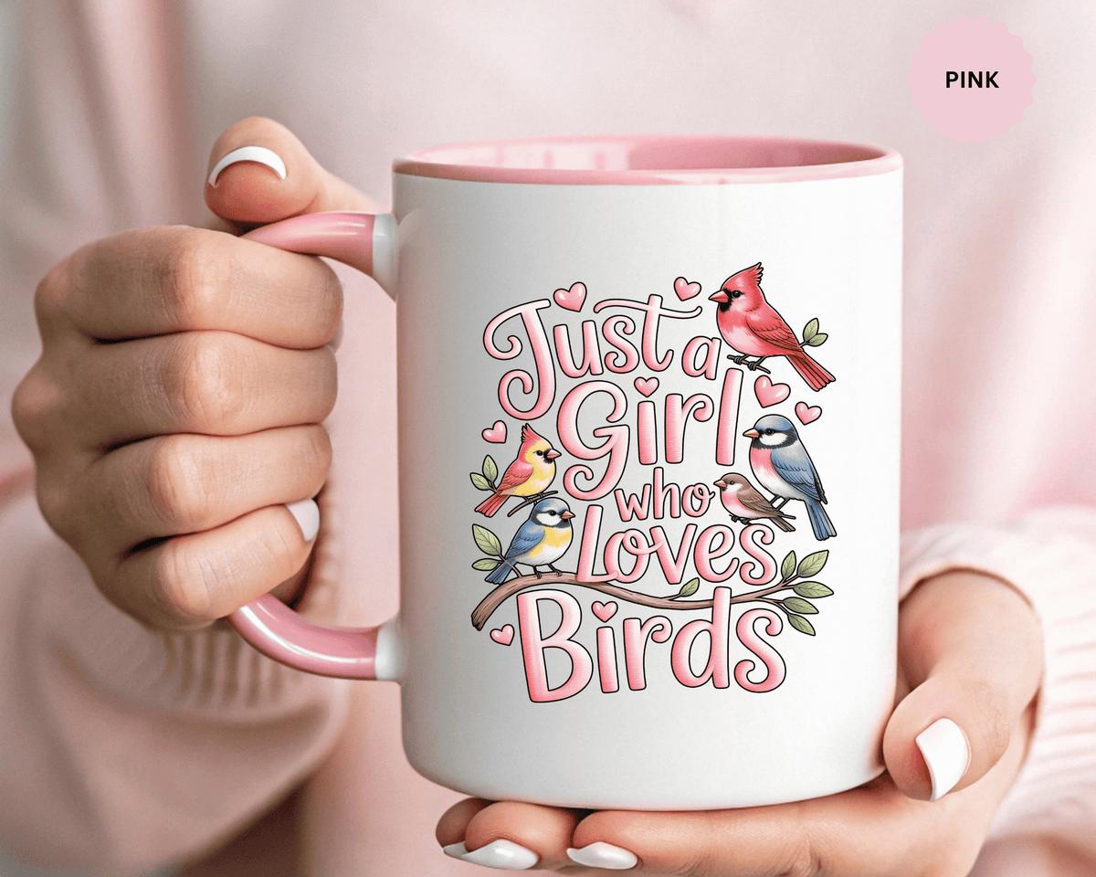 A white ceramic mug with a colored handle and interior, printed with "Just a Girl who Loves Birds" in pink lettering with a cardinal, blue birds and finches perched on a branch, with small hearts.