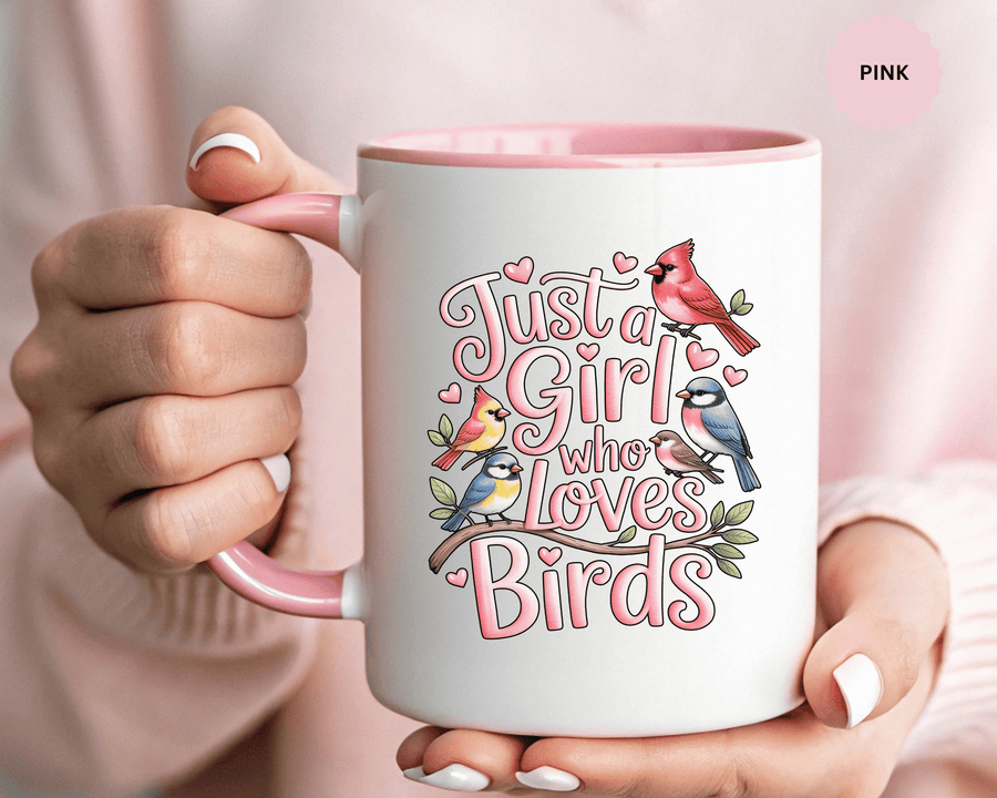 A white ceramic mug with a colored handle and interior, printed with "Just a Girl who Loves Birds" in pink lettering with a cardinal, blue birds and finches perched on a branch, with small hearts.