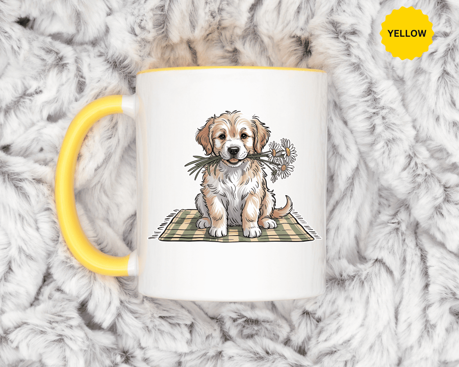 A white ceramic mug with a colored handle and interior, printed with a fluffy cream and tan puppy holding white daisies in its mouth, sitting on a green gingham blanket.