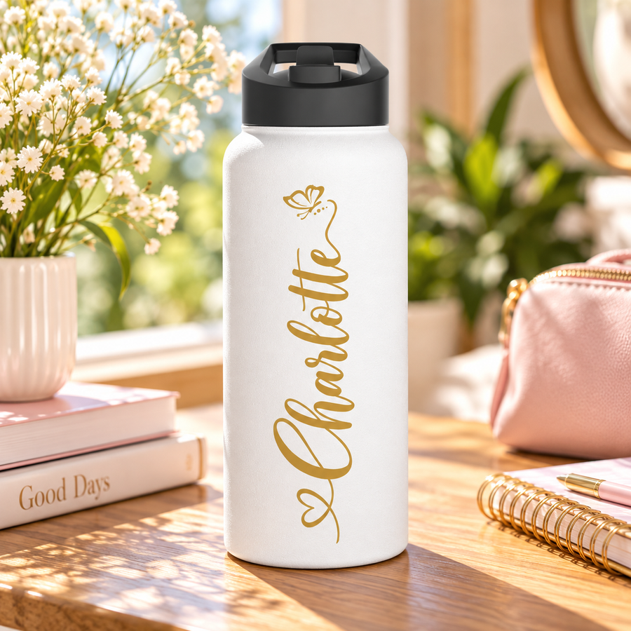 A white stainless steel water bottle with a black flip-top lid, printed with the sample name "Charlotte" in gold script running down the side, with a small gold butterfly at the top and a looped heart flourish at the bottom.