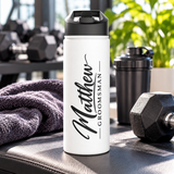A white stainless steel water bottle with a black flip-top lid, printed with the sample name "Matthew" in large black script running down the side, beside "GROOMSMAN" in black capitals between two thin lines.