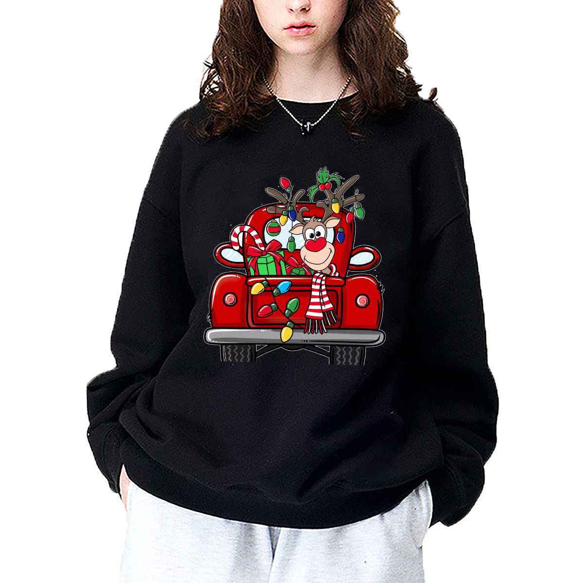 A black crewneck sweatshirt printed with a smiling reindeer riding in a red truck strung with Christmas lights.