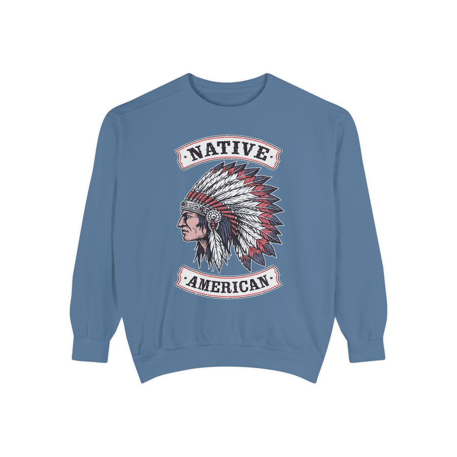 A blue crewneck sweatshirt printed with a profile of a figure in a red, white and blue feathered headdress between Native American banners.