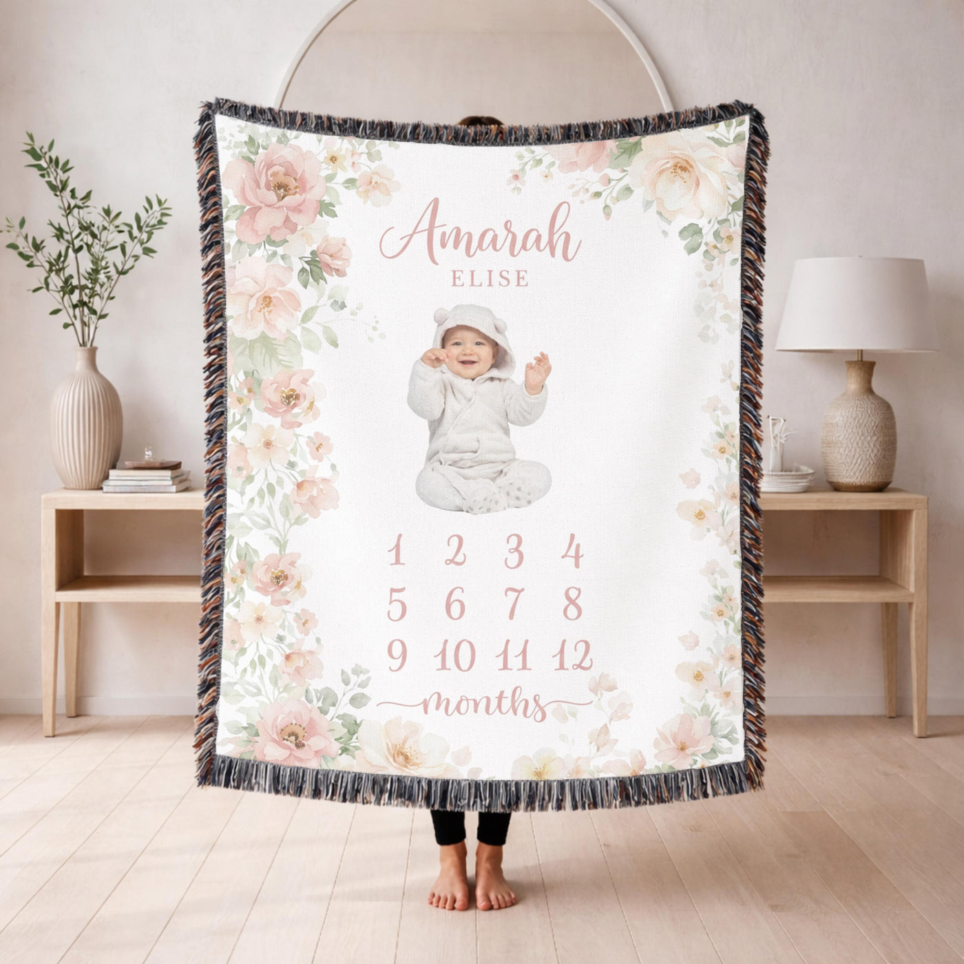 Fringed woven milestone blanket bordered with blush and cream watercolour roses and eucalyptus, printed with the name Amarah Elise and the numbers 1 to 12 beneath the word months.