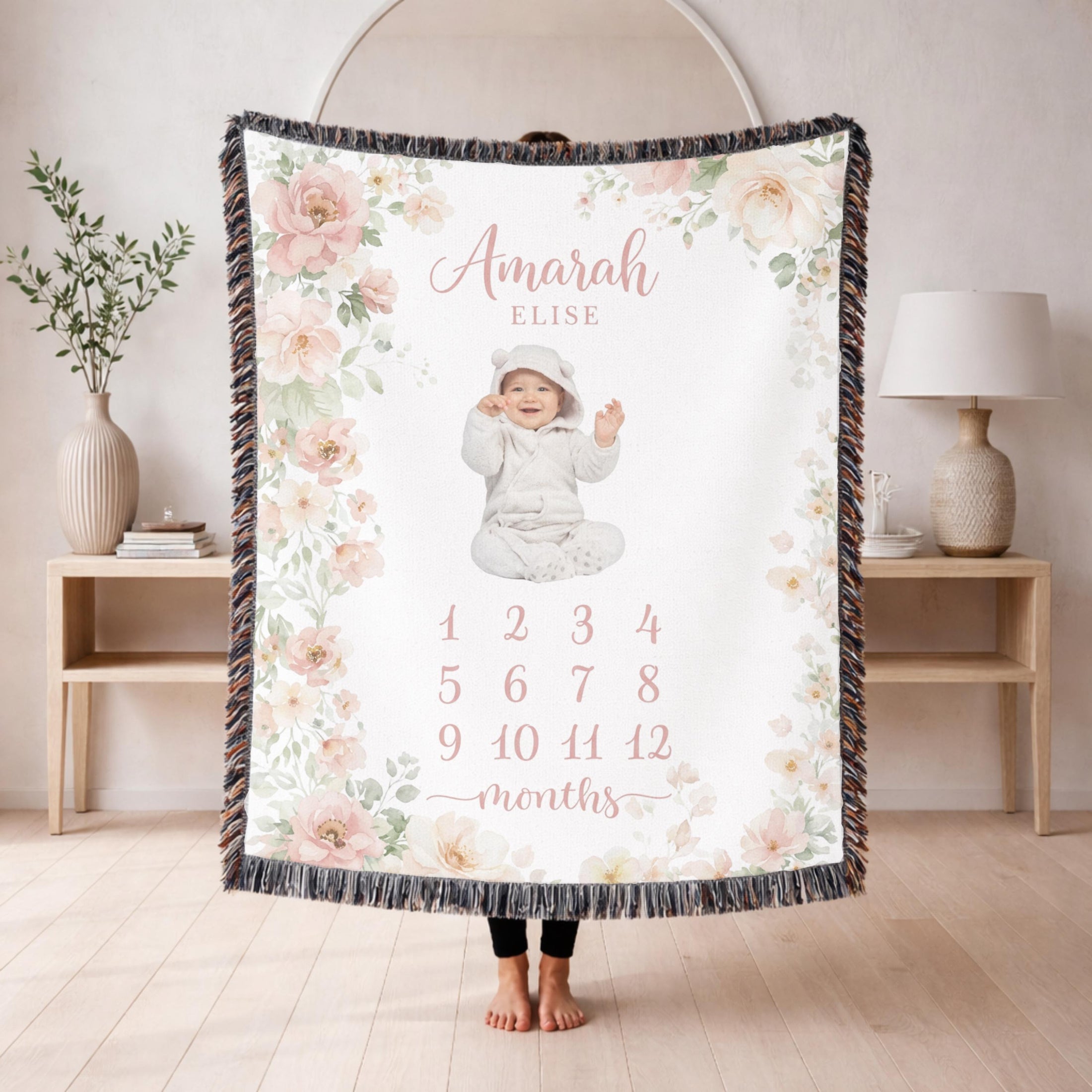 Fringed woven milestone blanket bordered with blush and cream watercolour roses and eucalyptus, printed with the name Amarah Elise and the numbers 1 to 12 beneath the word months.