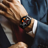Wheel-rim style watch with a black metal band, worn on wrist with a suit and tie