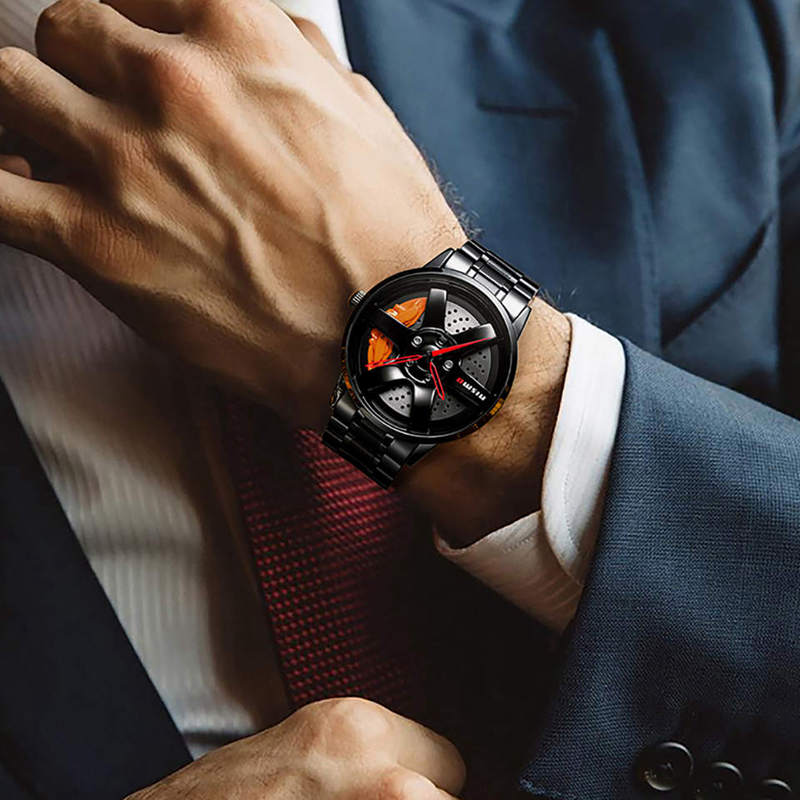 Wheel-rim style watch with a black metal band, worn on wrist with a suit and tie