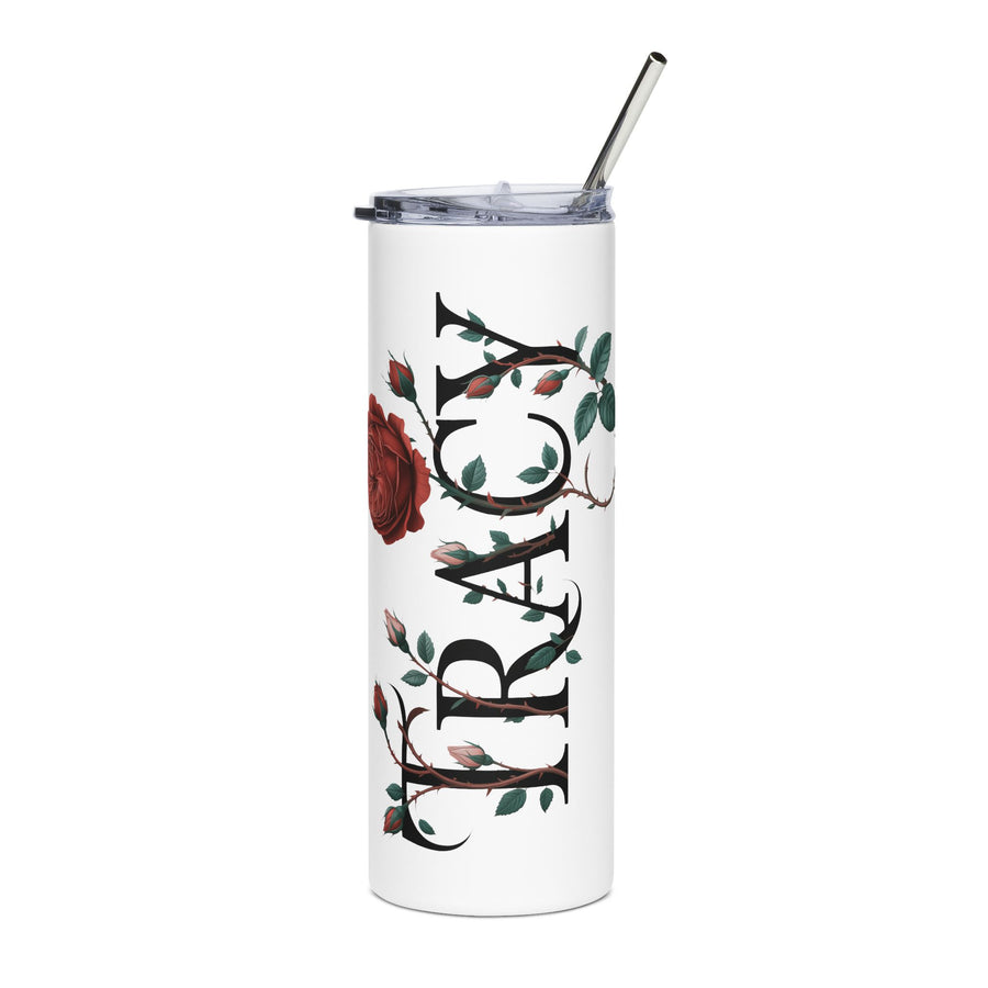 A white stainless steel skinny tumbler with a clear straw lid, printed with the sample name "Tracy" in a rose-and-thorn design, on a dressing table with makeup brushes.