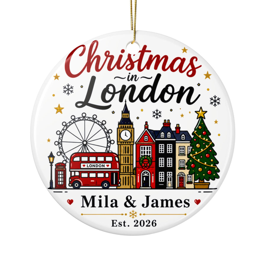 A round white ceramic Christmas ornament on a gold string, printed with "Christmas in London" above the London Eye, a red double-decker bus, Big Ben, townhouses and a Christmas tree, with sample couple names and "Est. 2026".