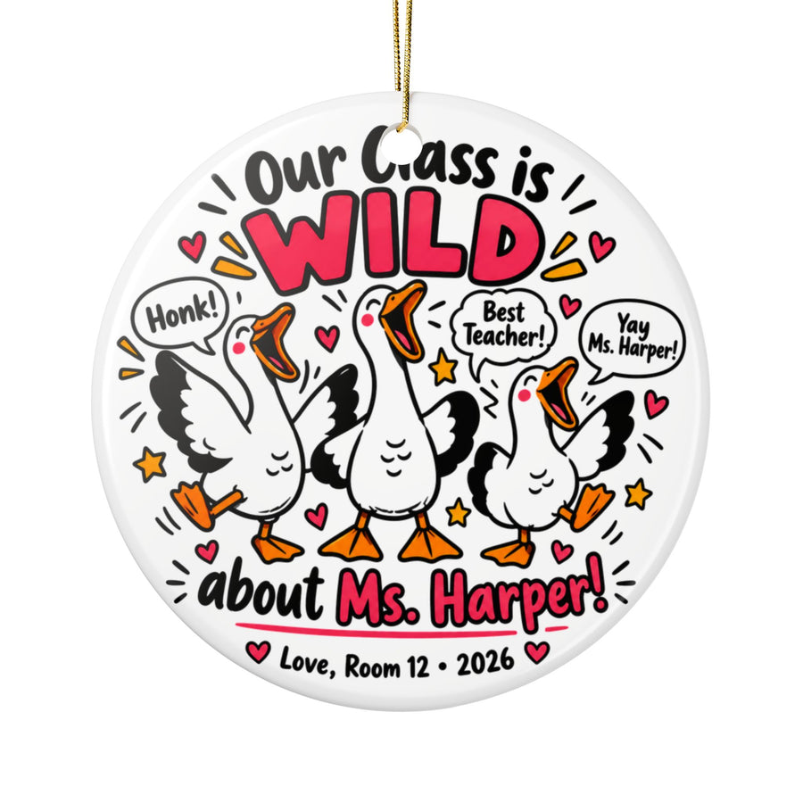 A round white ceramic Christmas ornament on a gold string, printed with "Our Class is WILD about" a sample teacher name in black and pink lettering around three cartoon white geese honking, with speech bubbles reading "Honk!", "Best Teacher!" and a cheer, hearts, stars and a room-number signature with "2026".