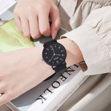 All-black minimalist watch with a round dial, shown worn on a wrist