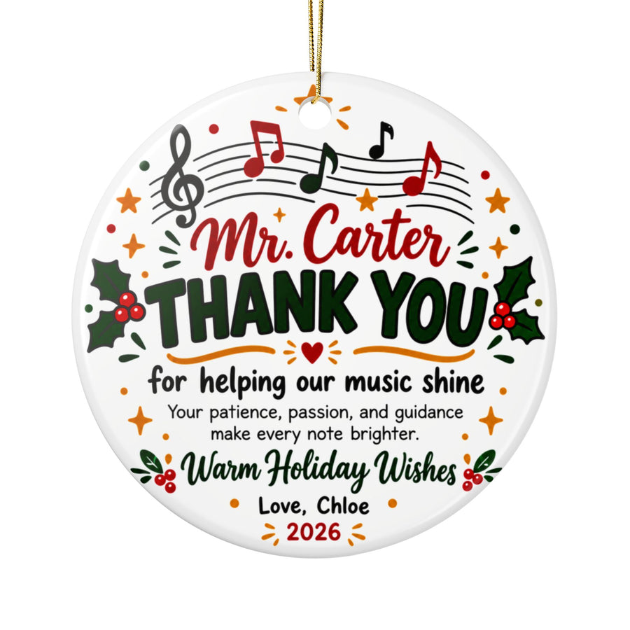A round white ceramic Christmas ornament on a gold string, printed with a treble clef and red, green and black notes on a staff above a sample teacher name, "THANK YOU for helping our music shine", a short note of thanks, holly, "Warm Holiday Wishes" and a "Love" signature with "2026".