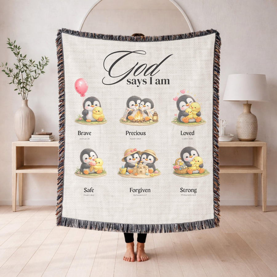 Cream fringed woven blanket headed God says I am, printed with six watercolour penguin and chick scenes labelled Brave, Precious, Loved, Safe, Forgiven and Strong with verses.