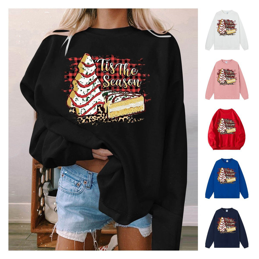 A black crewneck sweatshirt printed with a frosted Christmas tree cake over buffalo plaid and the words 'Tis the Season, shown with smaller images of other colors.