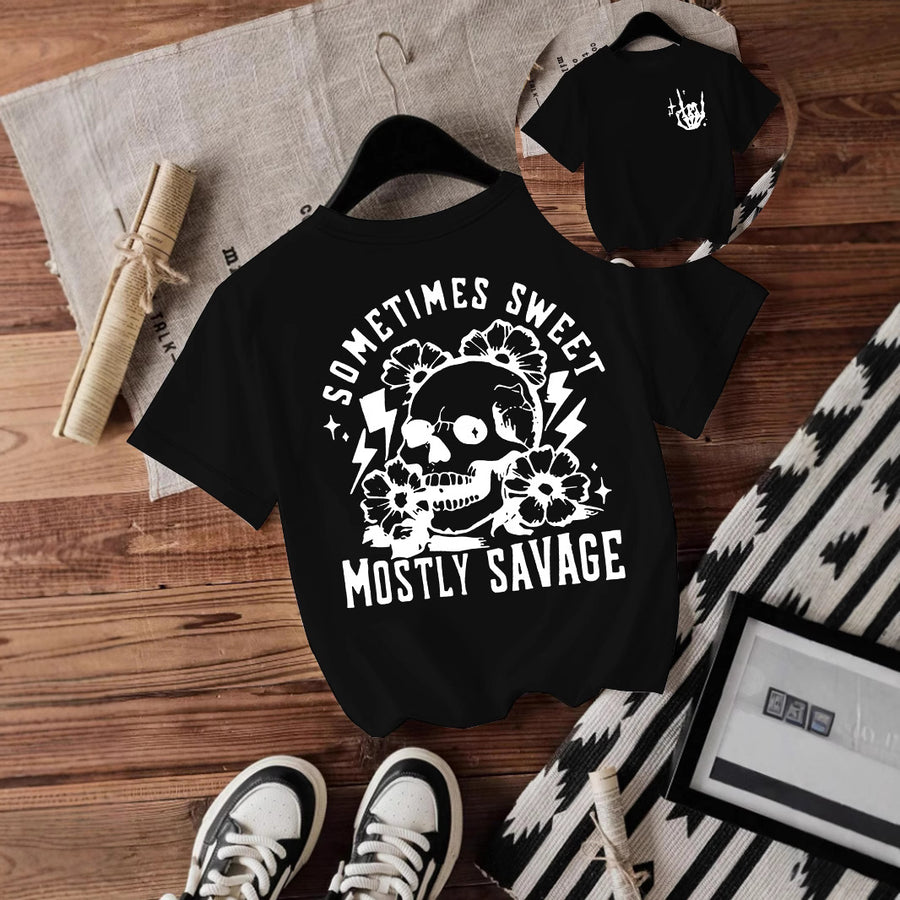 A maroon T-shirt printed with a white skull surrounded by flowers and lightning bolts between Sometimes Sweet and Mostly Savage.