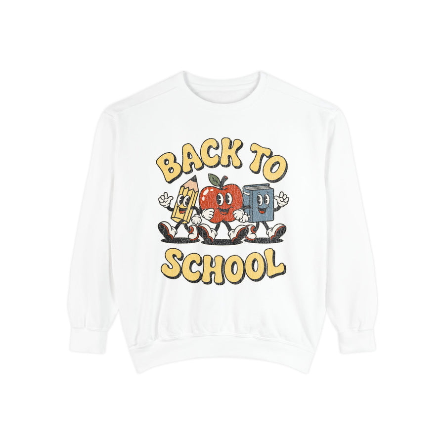 A white crewneck sweatshirt printed with a cartoon pencil, apple and book walking together under Back to School in yellow bubble letters.
