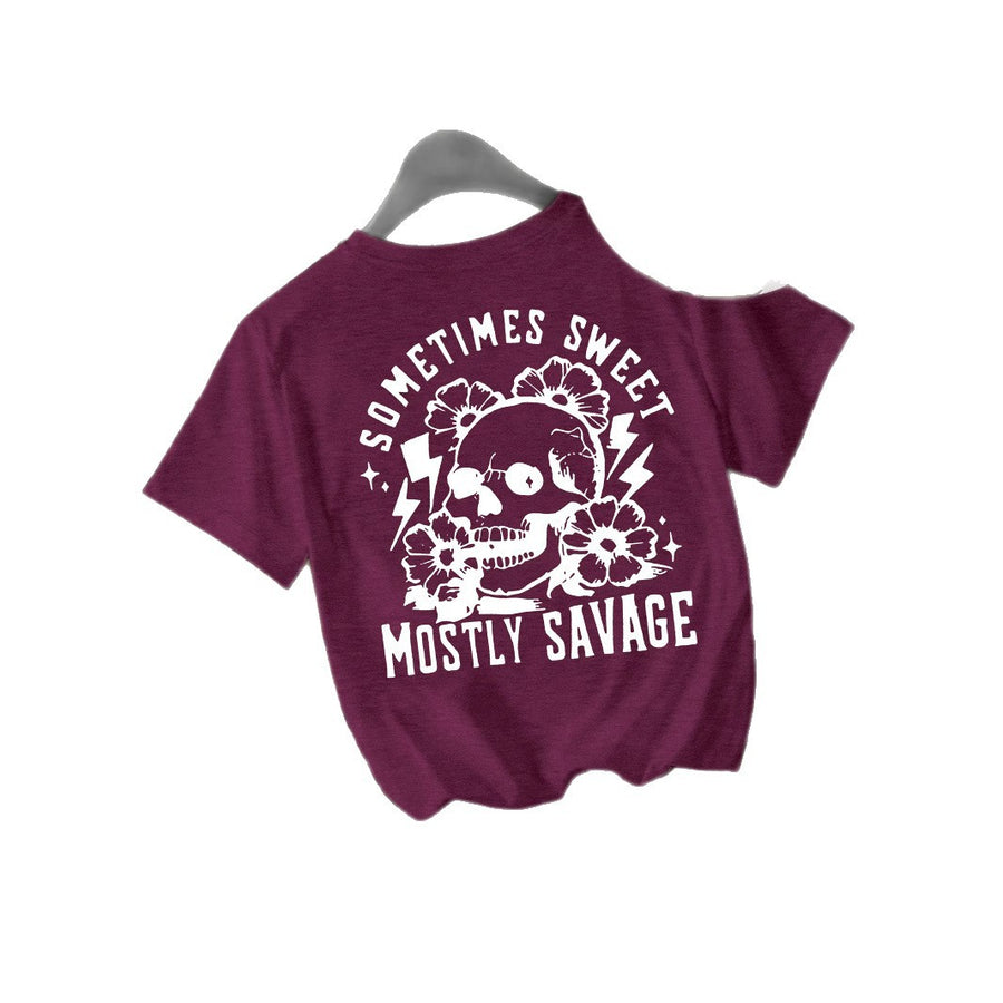 A maroon T-shirt printed with a white skull surrounded by flowers and lightning bolts between Sometimes Sweet and Mostly Savage.