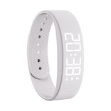 White silicone fitness band with a built-in digital display showing time and step count, in a seamless wraparound strap design.