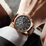 Rose gold chronograph watch with brown leather band and moon-phase dial, worn on wrist