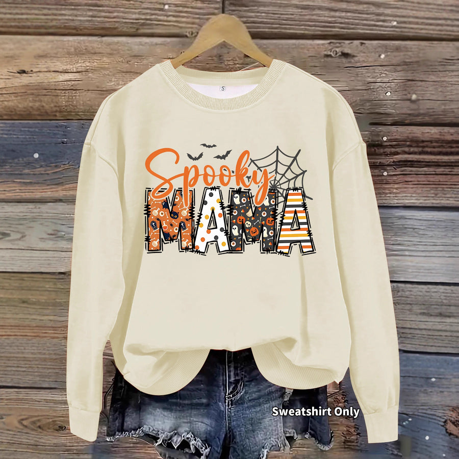 A brown crewneck sweatshirt printed with Spooky Mama in orange script over patterned block letters with a spider web.
