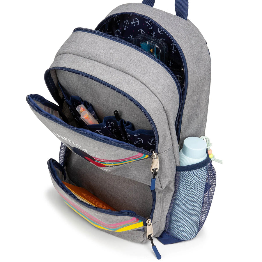 A heather gray Nautica kids backpack with navy trim, printed with a colorful striped double-heart design and repeating Nautica logo text, with a mesh side pocket and top handle.