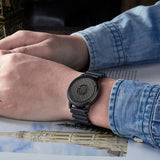 Black quartz watch with a magnetic ball bearing dial worn on a wrist with a metal bracelet