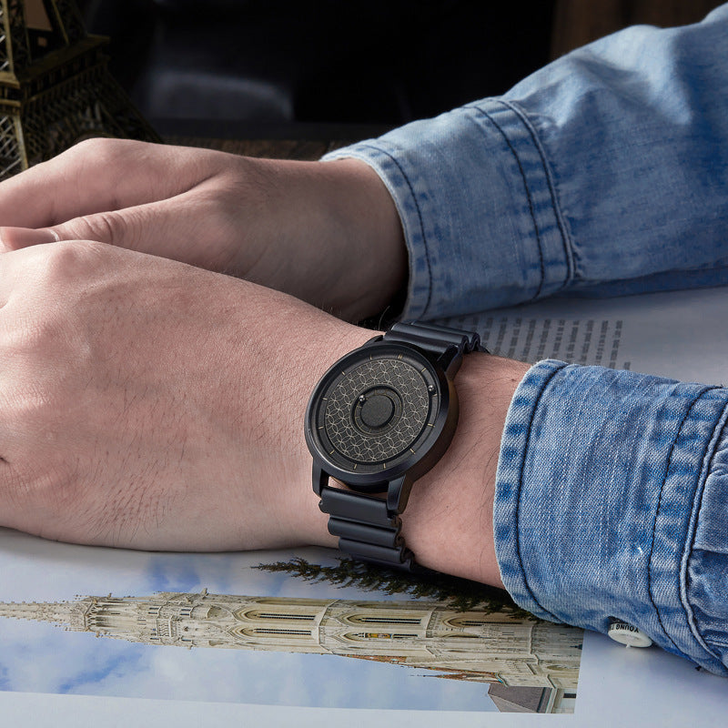 Black quartz watch with a magnetic ball bearing dial worn on a wrist with a metal bracelet