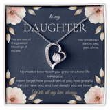 Silver heart-shaped pendant set with a solitaire stone and a row of small stones, displayed in a gift box on a navy card headed to my Daughter and framed with pink blossoms.